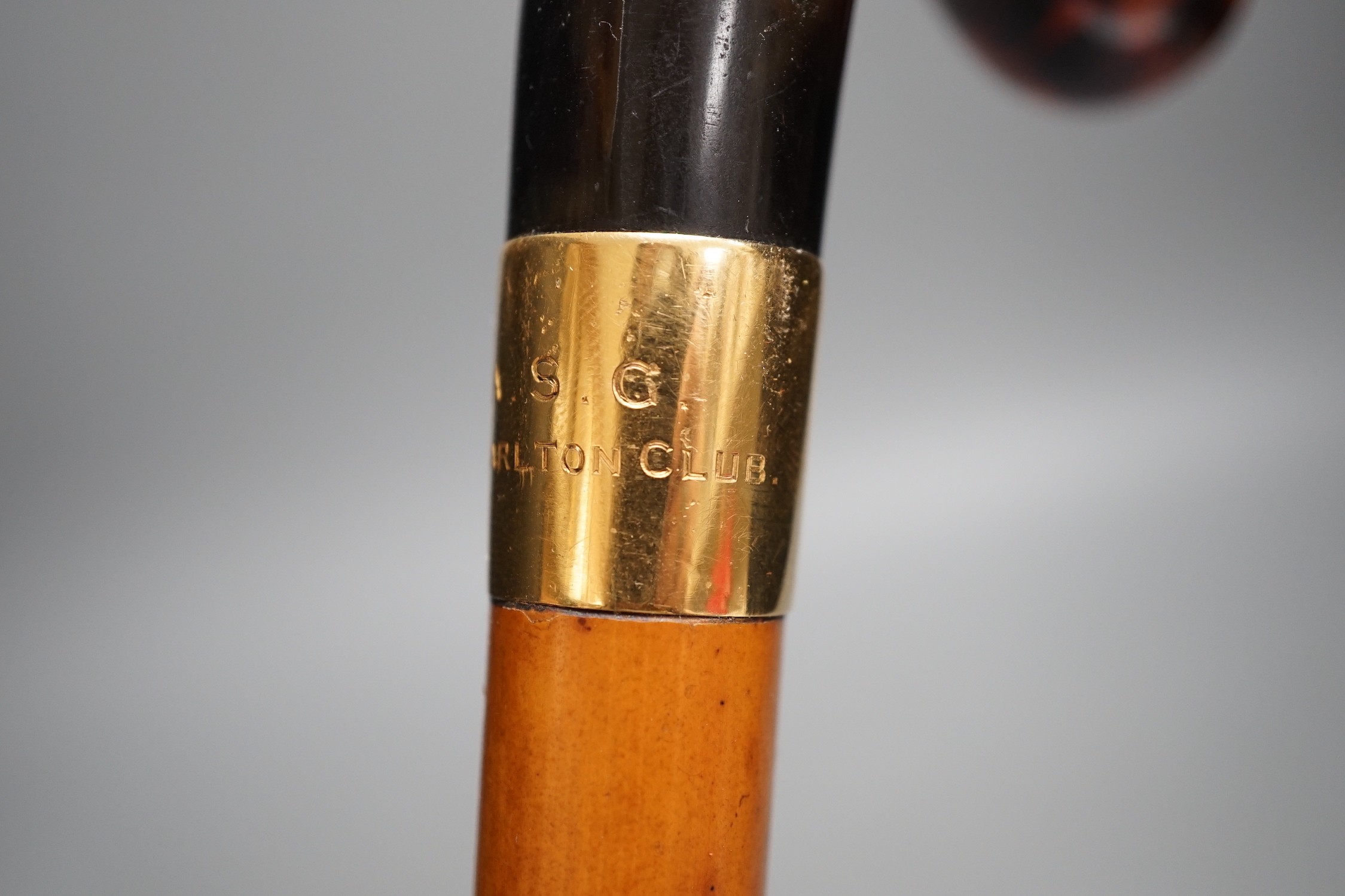 An 18ct gold collared malacca cane, with a horn handled handle, stained as tortoiseshell, 94 cms long